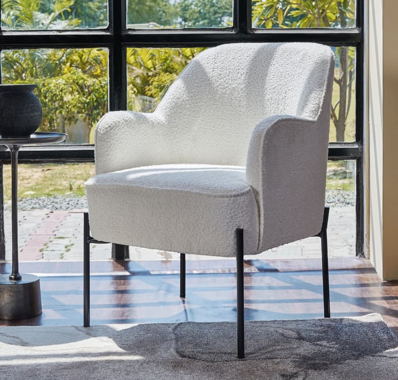 A light and airy cotton bouclé accent chair in a casual living space, bright room, relaxed styling, indoor plant, soft daylight

