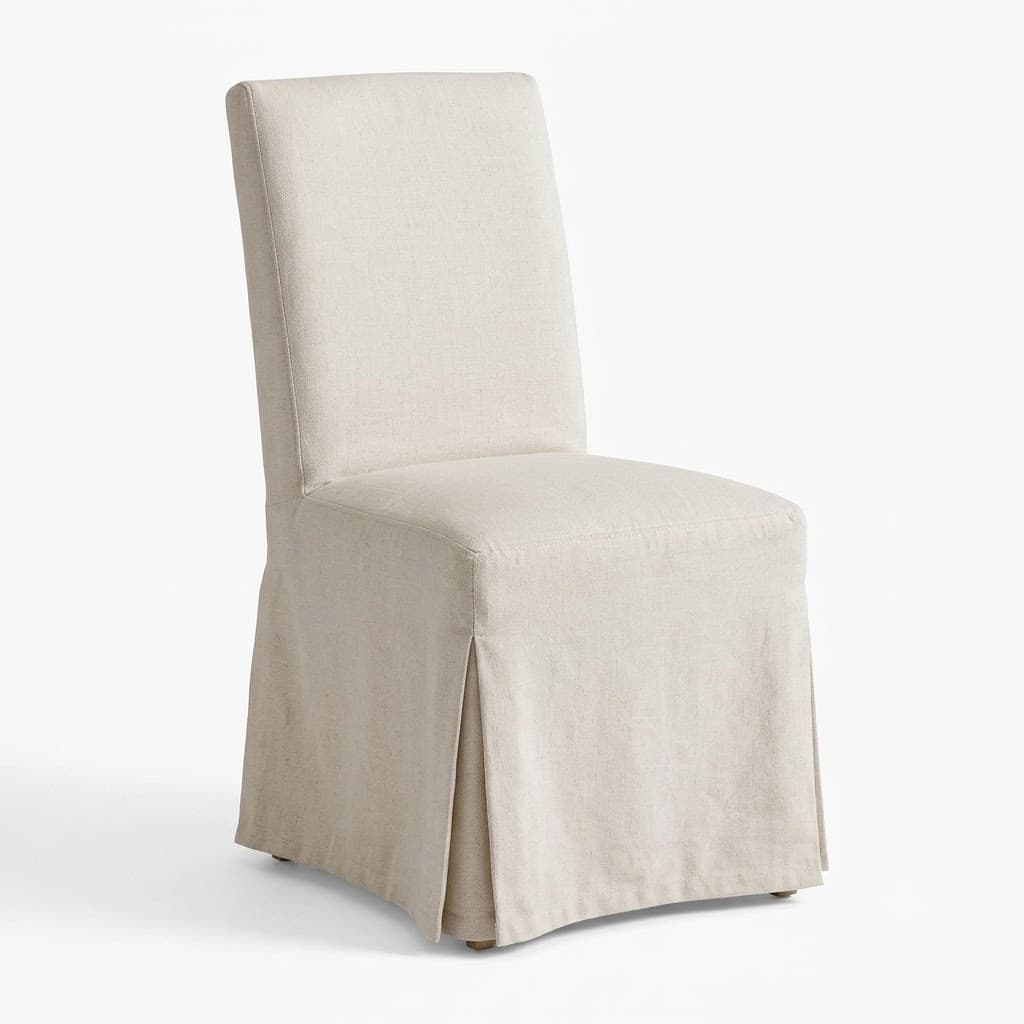 Slipcovered linen dining chair with a pleated skirt.